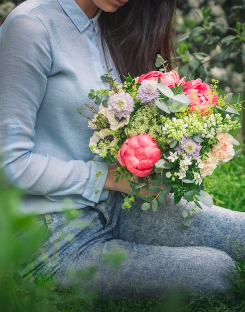 Uma Mulher Segurando Um Buquê De Flores Coloridas Do Verão E Sentado Na Grama Foto Grátis 