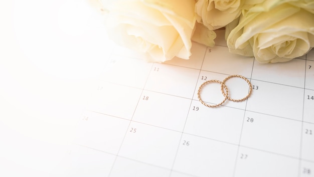 Uma visão aérea de alianças no calendário com rosas Foto gratuita