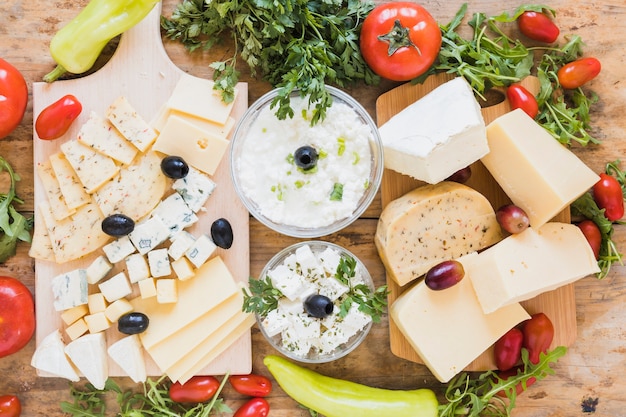 Uma visão aérea de prato de queijo fresco com azeitonas; salsinha; tomates e rúcula folhas na mesa de madeira Foto gratuita