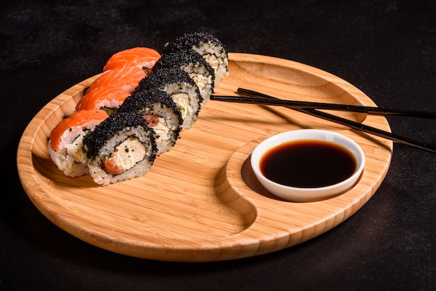Vários tipos de sushi serviram em um escuro. rolo com salmão, abacate, pepino. menu de sushi. comida japonesa Foto Premium