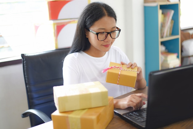 Venda de entrega de compras on-line de comércio eletrônico on-line de envio e ordem inicialização pequena empresa proprietária trabalhando conceito - jovem mulher embalagem caixa de papelão parcela entrega ao cliente dinheiro na entrega Foto Premium