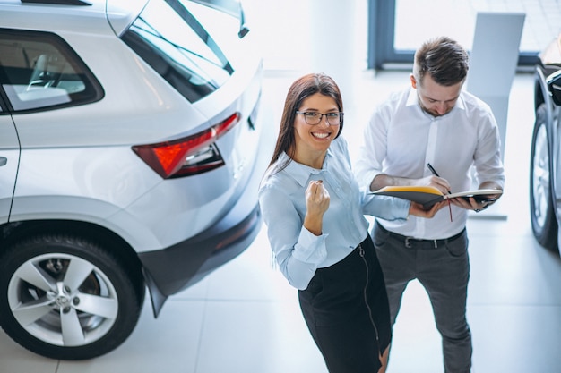 Vendedor E Mulher Procura De Um Carro Em Um Showroom De Carros Foto