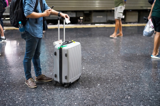 Viajante com bagagem na estação de trem para viagens Foto Premium