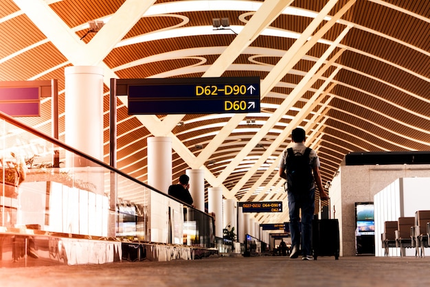 Viajante com mala de viagem ou bagagem andando no aeroporto passarela terminal para viajar de avião Foto Premium