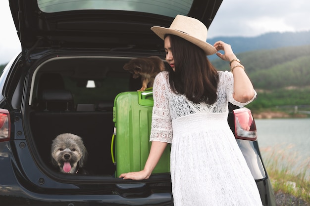 Viajante feliz da jovem mulher que senta-se no carro do carro com cães. Foto Premium