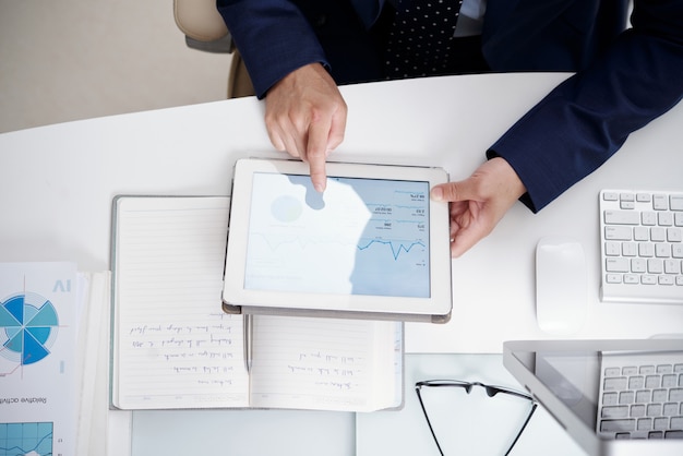Vista superior da área de trabalho do escritório com notebook, documentos, computador e tablet digital usado por homem anônimo Foto gratuita