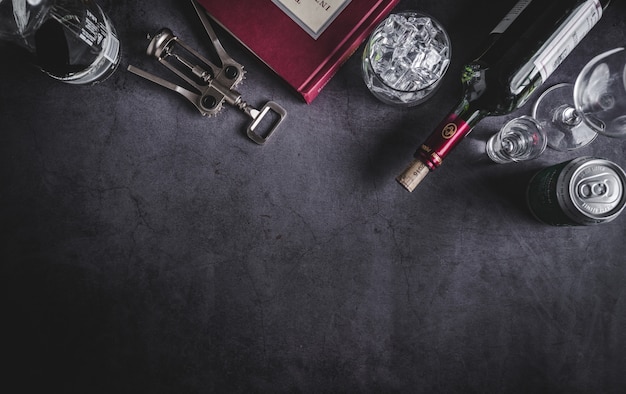 Vista superior da garrafa de vinho, garrafa de vodka, cubo de gelo, cerveja e saca-rolhas Foto Premium