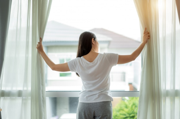 Vista traseira da mulher asiática acordando em sua cama ...