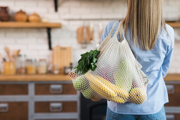 Vista traseira mulher carregando sacola reutilizável frutas