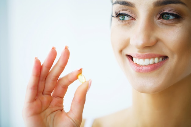 Vitaminas. alimentação saudável. menina feliz com a cápsula do óleo de peixes omega-3. conceito de dieta saudável. Foto Premium