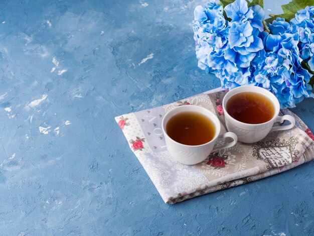 Xícara de chá no fundo azul com flores e têxteis Foto Premium