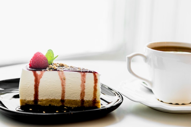 Xícara de chá perto do cheesecake caseiro com frutas frescas e hortelã para a sobremesa na mesa Foto gratuita