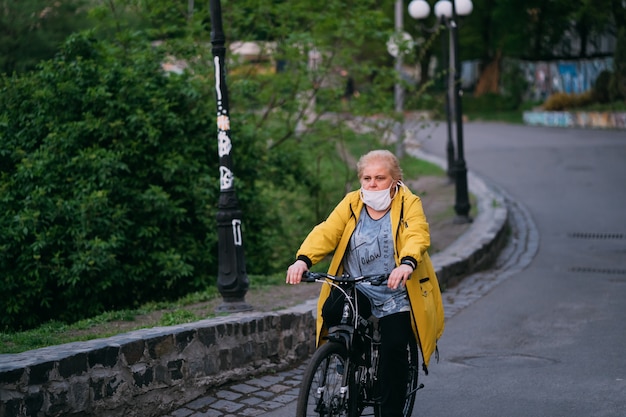 Alte frau auf seinem fahrrad mit einer chirurgischen maske