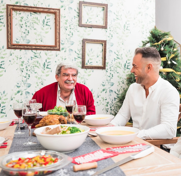 Alter mann, der mit sohn am festlichen tisch spricht Kostenlose Fotos