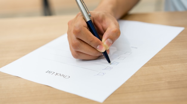 Angestelltmannhand unter verwendung des stiftes für das überprüfen der liste Premium Fotos