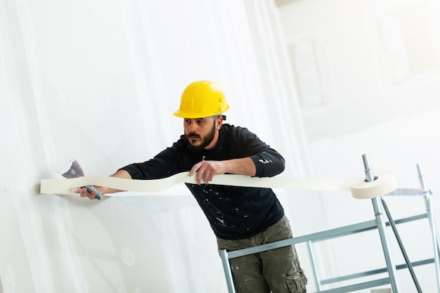 Arbeitskraft, die gipskartonwand vergipst. Premium Fotos
