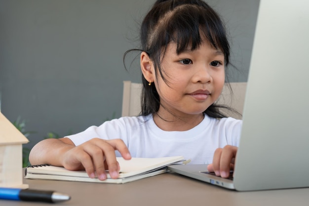 Asiatische studentin, die den laptop für den online