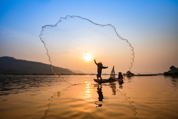 Asien-fischernetz unter verwendung des hölzernen boot casting-netzsonnenuntergangs oder -sonnenaufgangs im mekong Premium Fotos