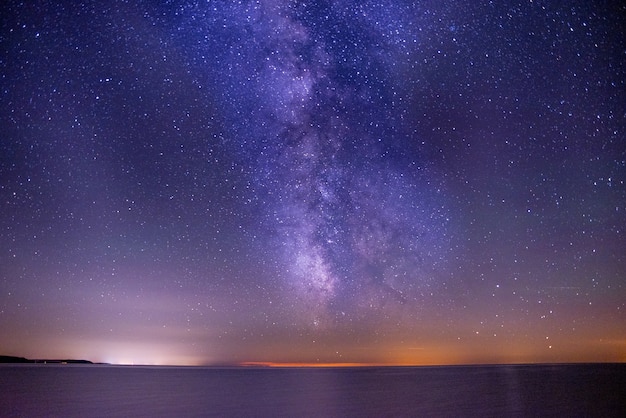 Atemberaubende Aufnahme Des Meeres Unter Einem Dunklen Und Lila Himmel Voller Sterne Kostenlose Foto