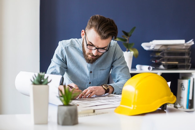 Attraktiver männlicher ingenieurzeichnungsplan auf plan am arbeitsplatz Kostenlose Fotos
