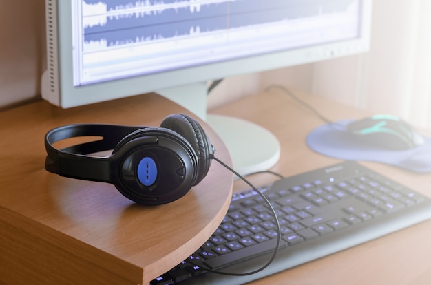 Auf dem hölzernen desktop des sounddesigners liegen große schwarze kopfhörer Premium Fotos