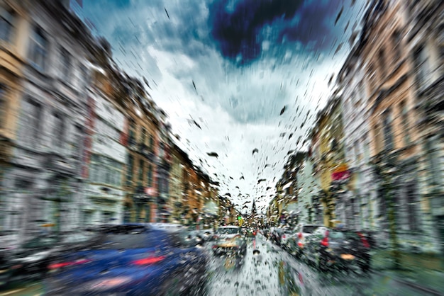 Autowindschutzscheibe mit regen fällt während des sturms und der unscharfen bremslichter Premium Fotos