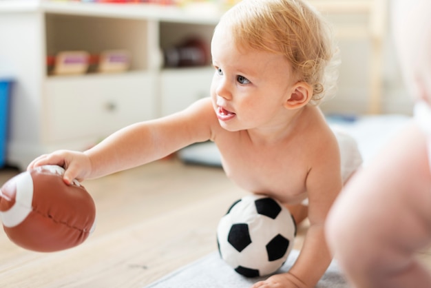 Baby, das mit sportbällen spielt Premium Fotos