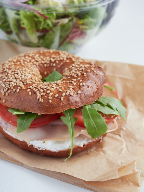 Bagel Gefullt Mit Rucola Putenschinken Frischkase Und Tomate Auf Geschenkpapier Salat Auf Teilansicht Verschwommener Wand Wegnehmen Premium Foto