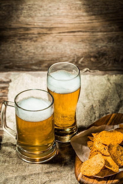 Bier im becher, glas auf hölzernem hintergrund PremiumFoto