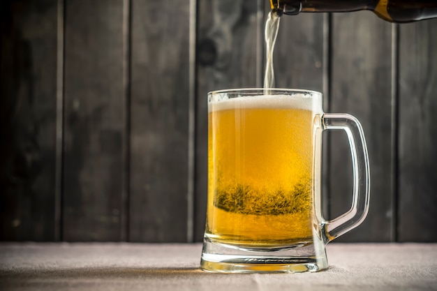 Bier in einem glas gießt aus einer flasche. PremiumFoto