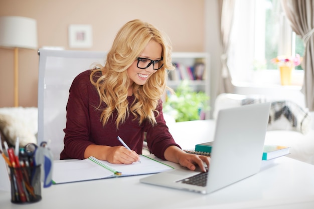 Blondes mädchen, das laptop während des studiums zu hause