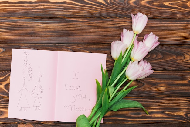 Blumen und kinderzeichnung mit text ich liebe dich mutter auf hölzerner tabelle Kostenlose Fotos