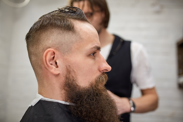 Brutaler Typ Im Modernen Friseurladen Friseur Macht Frisur Zu Einem Mann Mit Langem Bart Meister Friseur Macht Frisur Mit Haarschneider Premium Foto