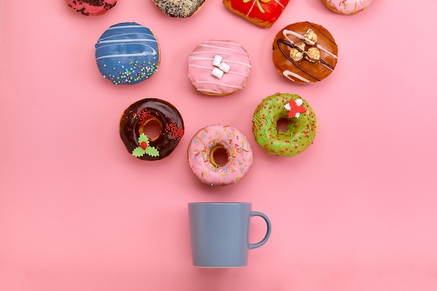 Bunte donuts mit zuckerguss und kaffeetassen auf pastellfarbener ...