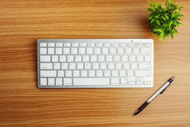 Computertastatur und ein stift auf hölzernem schreibtischhintergrund. Premium Fotos