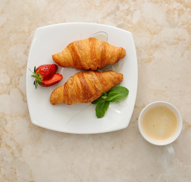 Croissants mit kaffee, erdbeeren und minze | Premium-Foto