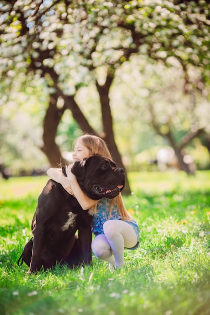 Das bezaubernde kind, das einen schwarzen hund umfaßt Kostenlose Foto