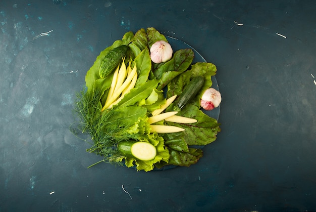 Das gemüse im kasten auf dem stein ein dunkel. junge grüne zwiebel knoblauch zucchini helle gewürze sind in einer holzkiste mit seilgriffen auf einem dunkelen strukturierten. Premium Fotos
