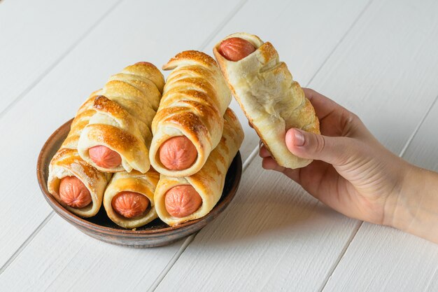 Das kind nimmt eine frisch gekochte hausgemachte wurst in den teig aus der tonschüssel. Premium Fotos