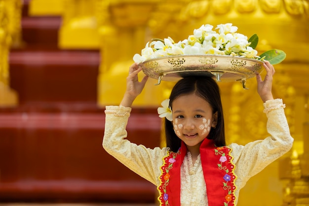 Das mädchen in mon-tracht überreicht dem mönch an einem religiösen tag ein tablett in blumengröße. Premium Fotos
