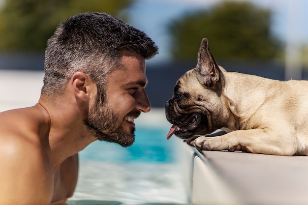 Der hund und sein besitzer sind am pool ein lächelnder mann mittleren