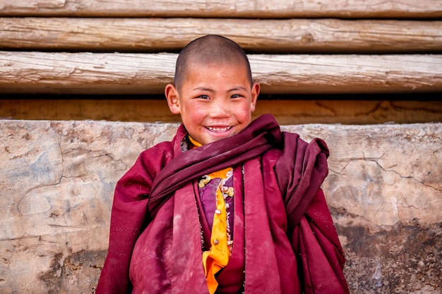Der kleine junge, der von den buddhistischen anfängermönchen lächelt, betet in boudhanath-kloster Premium Fotos