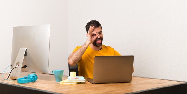 Der mann, der mit laptot in einem büro arbeitet, macht lustiges und verrücktes gesichtsgefühl Premium Fotos