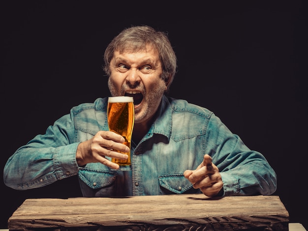 Der schreiende mann im jeanshemd mit einem glas bier