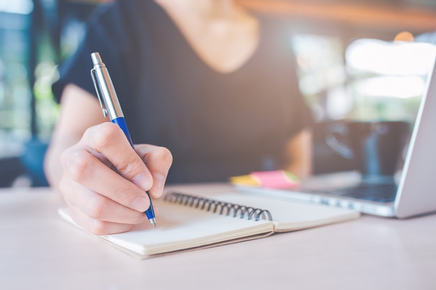 Die hand der geschäftsfrau schreibt auf ein notizbuch mit einem stift. Premium Fotos