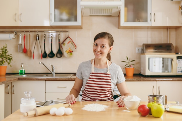 Die junge schöne glückliche frau bereitet teig für kuchen