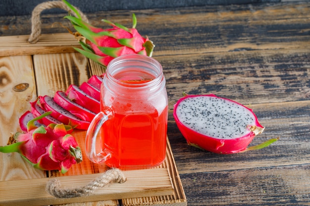 Drachenfrucht mit saft in einem tablett auf holztisch, hohe ...
