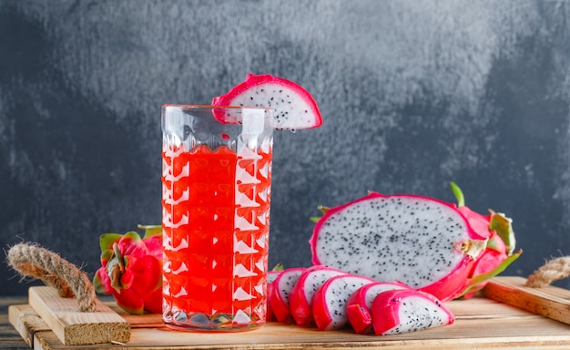 Drachenfrucht mit saft in einem tablett auf holztisch und gipswand ...