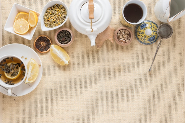 Draufsicht der teekanne; teesieb; zitronenscheibe; trockene grapefruit und getrocknete chinesische chrysanthemenblüten auf tischset Kostenlose Fotos