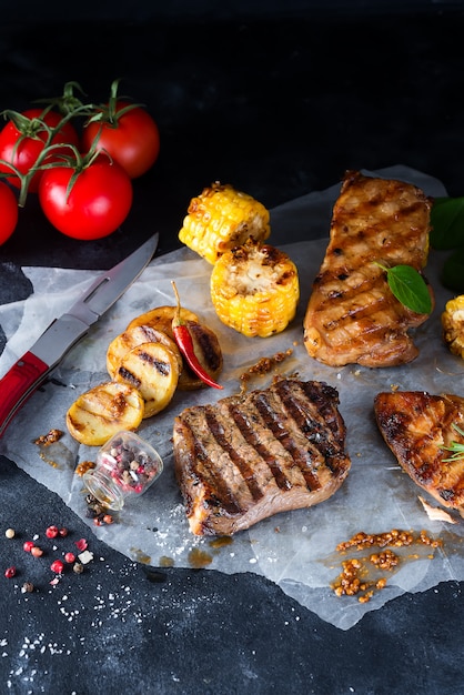 Drei arten von gegrilltem fleisch mit gemüse und gewürzen auf papier Premium Fotos